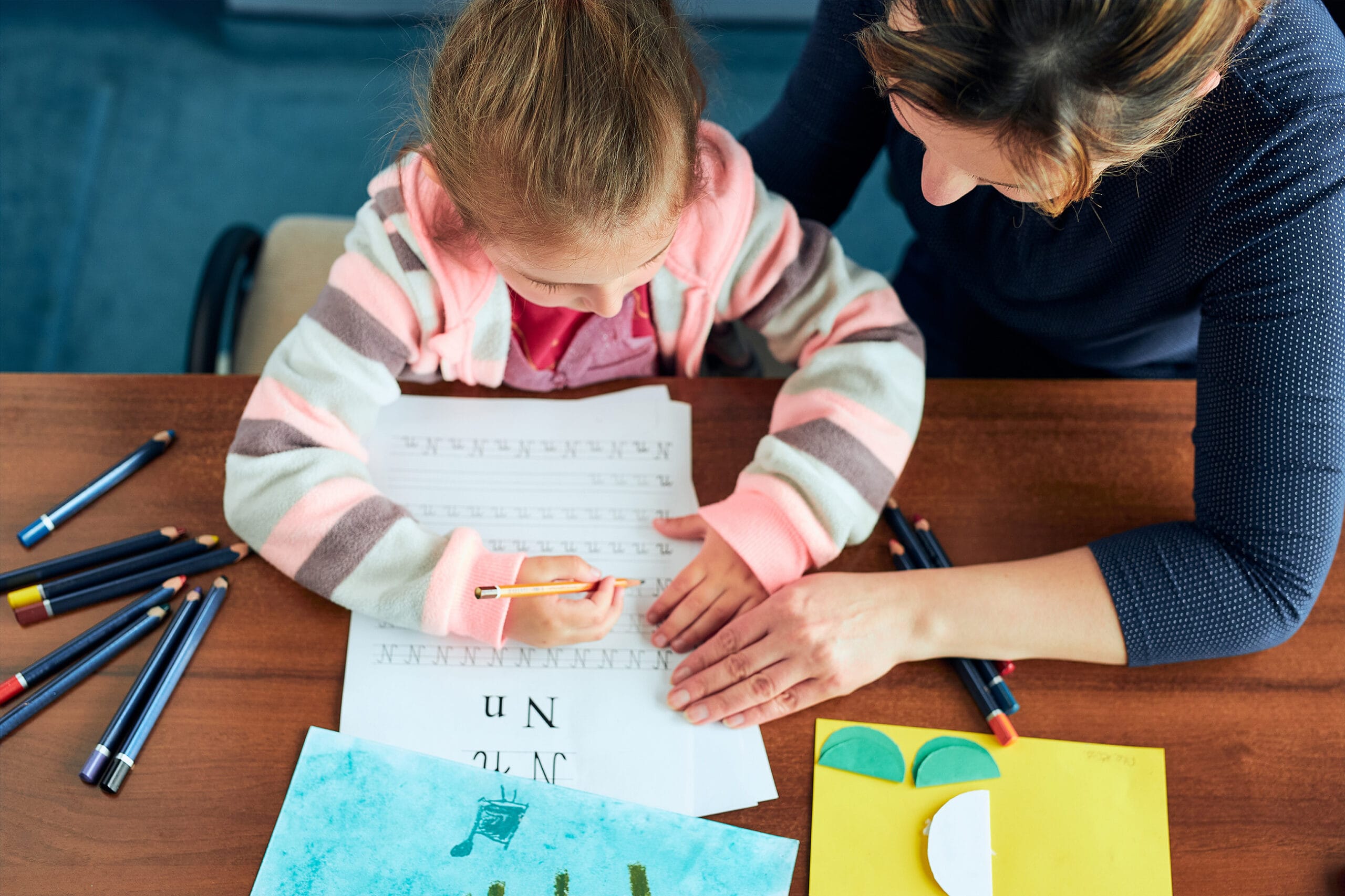 Little girl preschooler learning to write letters with help of h Baner